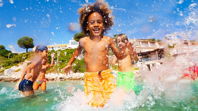 African boy playing with friends in shallow water