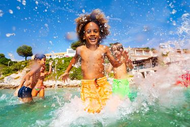 African boy playing with friends in shallow water